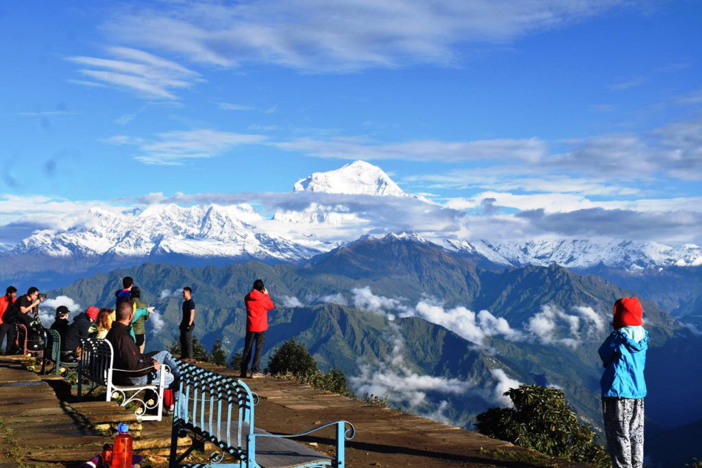 म्याग्दीको घार– १ मा पर्ने पुनहिलबाट धौलागिरी हिमाल र पहाडी दृश्यावलोकन गर्दै पर्यटक । तस्बिरः सन्तोष गौतम, रासस