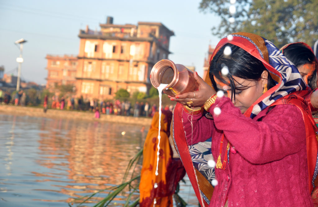 भक्तपुरको कमलविनायकस्थित कमलपोखरीमा सोमबार उदाउँदो सूर्यलाई अर्घ दिई छठ पर्वको समापन गर्दै ब्रतालु महिला । तस्बिरः लक्ष्मी गारु, भक्तपुर, रासस